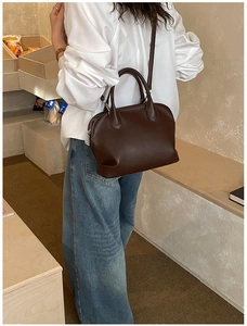 Detail view of a dark brown Boston bag with smooth leather finish and adjustable strap