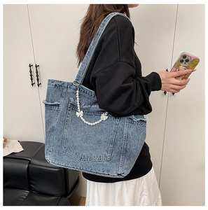 Detail of light blue denim tote bag with decorative pearls, ribbon and frayed edges