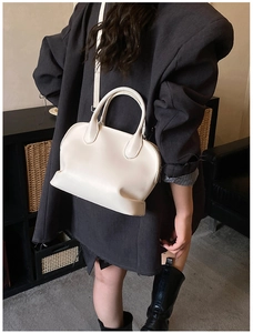 Minimalist white leather bowling bag styled with a dark blazer for a chic casual look