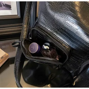 Detail of the front zipper pocket on a black crocodile pattern tote bag showing storage space