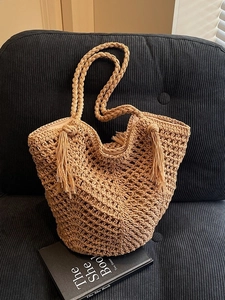 Sac cabas tissé en corde de coton kaki avec pompons et doublure sur canapé noir