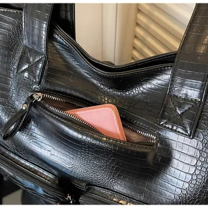 Macro view of the functional front zipper pocket on a black crocodile pattern tote bag