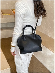 Lifestyle view of a black lychee texture shell bag worn as a shoulder and crossbody bag