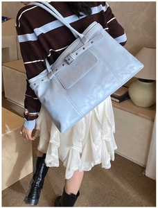 Gros plan du sac cabas bleu clair avec des rivets métalliques et des sangles en cuir