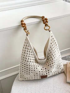 Hollow crochet tote bag with wooden bead handles and woven texture for beach vacation