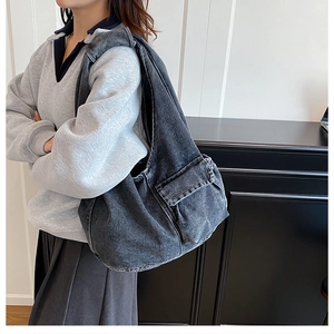 Detail of dark denim tote bag with functional cargo side pocket worn by model