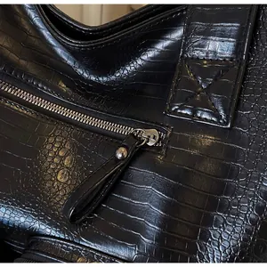 Detail of silver smooth zipper and black crocodile embossed leather on the tote bag