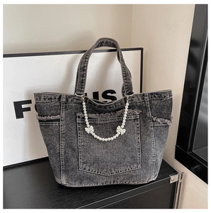 Detail of dark grey denim tote with pearl chain, bow accents, and frayed edges