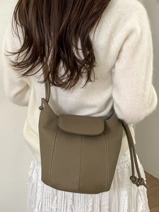 Sac seau vintage marron avec poignée supérieure et détails de cordon sur modèle blanc