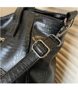 Detail of adjustable shoulder strap with silver buckle on black faux crocodile tote bag