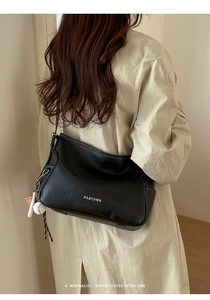 Detail of black leather crossbody bag featuring a PANTOR logo and baseball charm