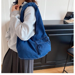 Detail of vintage blue denim shoulder bag featuring a large front flap pocket and stitching