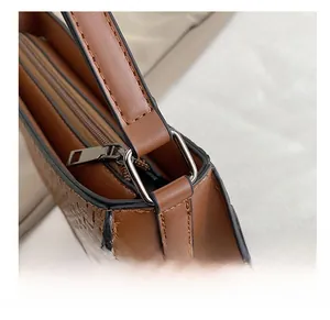 Detailed view of brown motorcycle bag featuring woven texture and silver square ring