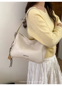 Detail of cream leather tote bag with PANTOOR logo and stylish tassel hanging on shoulder