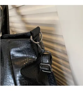 Detail of crocodile embossed leather tote with silver metal D-rings and adjustable strap