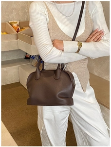 Detail of dark brown lychee leather shell bag with adjustable strap and handles