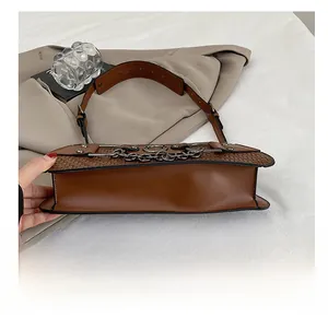 Detail of the brown leather shoulder bag featuring a wear-resistant flat bottom and stitching
