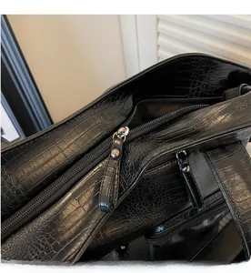 Detail of smooth metal zipper and crocodile embossed faux leather on black tote bag