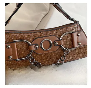 Detailed close-up of brown woven leather bag with metal rings and decorative chain