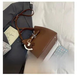 Detailed view of brown lychee grain leather bucket bag with silver lock and horse charm