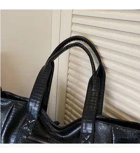 Detail of reinforced handles and crocodile texture on black large capacity tote bag