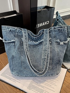 Light blue washed denim tote bag with frayed edges and multiple exterior pockets
