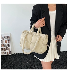 Detail of beige quilted puffer bag with thick handles and drawstring side details