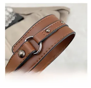 Detail of brown leather strap with vintage metal rivets and silver D-ring buckle