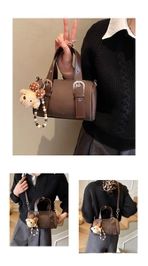 Detail of dark brown leather bowling bag showing silver buckle and plush bear charm