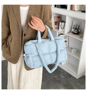 Detail of light blue quilted tote bag with side drawstring and soft nylon puffer texture