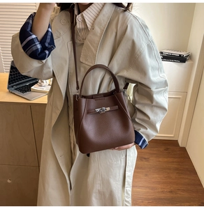 Detail of the litchi pattern leather bucket bag in dark brown with silver clasp