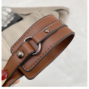 Macro shot of brown leather wristband with dark grey metallic studs and center ring detail
