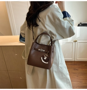 Close-up of brown litchi pattern leather bucket bag with metal lock and horse charm
