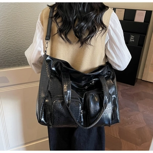 Detail view of large black crocodile pattern tote bag with functional front zippers