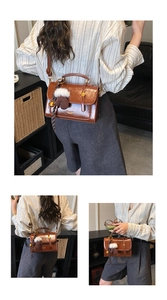 Detail der braunen Vintage-Klapptasche mit Handschuh-Anhänger und goldener Glocke