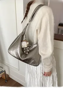 Detail of silver metallic hobo bag with pleated texture and plush charm on the shoulder strap