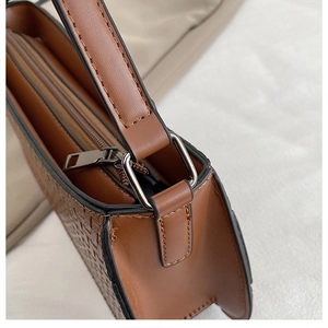 Detail of brown faux leather motorcycle bag with woven texture and metal hardware