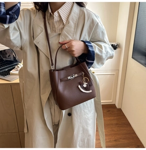 Detail of a brown lychee leather bucket bag featuring a silver twist lock and horse charm
