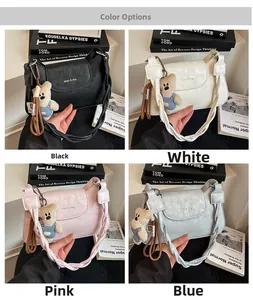 Detail view of stylish square shoulder bags in black, white, pink and blue with bear charm