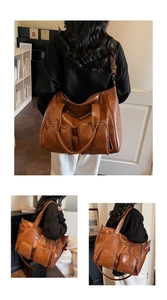 Close-up of brown crocodile embossed tote bag featuring two functional front zip pockets