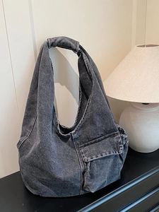 Vintage dark grey washed denim hobo shoulder bag with utility flap pocket on wood