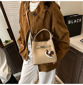 Close-up of beige lychee leather bucket bag with silver lock and horse charm detail