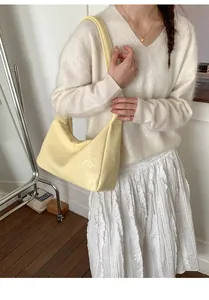 Detail of light yellow tote bag featuring a unique pleated texture and wide shoulder strap