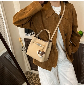 Detail of beige grained leather bucket bag with silver buckle and pony charm accessory