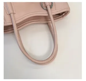 Détail du sac seau en cuir rose nude avec poignée ronde et quincaillerie en métal argenté