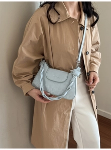 Detail of light blue crossbody bag with chunky braided handle and soft leather texture