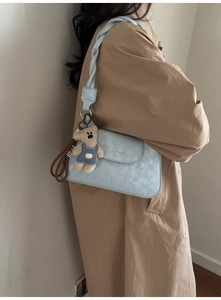 Light blue crossbody bag with woven strap and cute teddy bear charm accessory