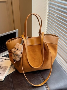 Sac fourre-tout vintage en daim et cuir marron avec charme d'ours sur un banc