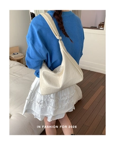 Detail of cream white textured hobo bag showing adjustable strap and soft leather material