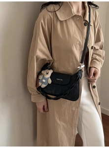 Detail of black leather crossbody bag with flap and cute bear plush pendant accessory